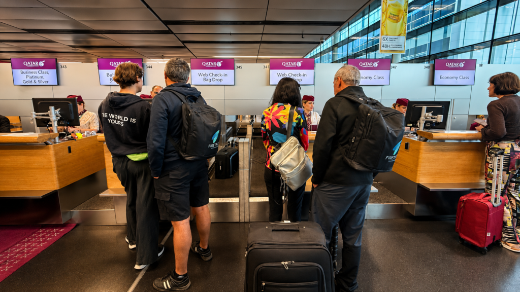 Cestující u odbavovacích přepážek Qatar Airways na letišti před odletem na Maledivy.