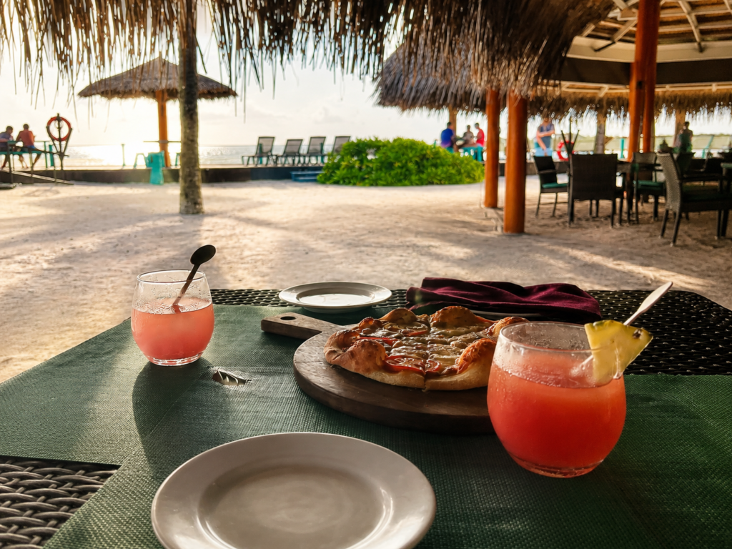Pizza a ovocné drinky na stole v pizza baru v resortu Adaaran Select Hudhuran Fushi na Maledivách.