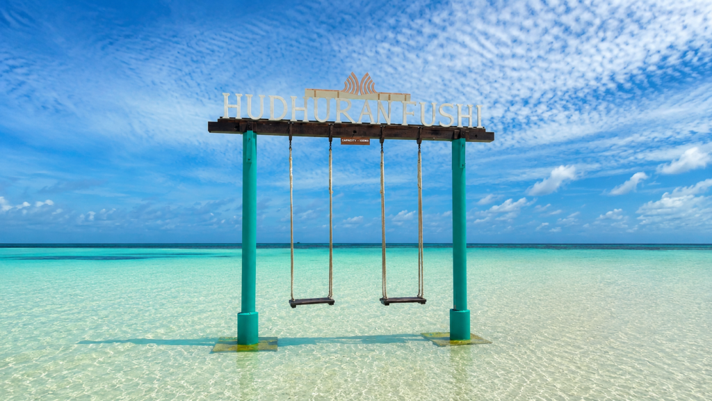 Maledivy v červnu s houpačkami v mělkém tyrkysovém moři u resortu Hudhuranfushi.