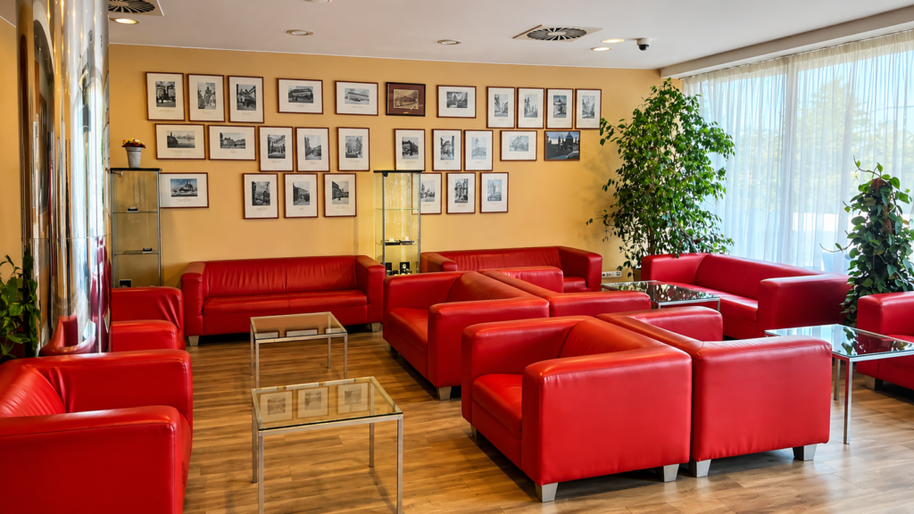 Lobby hotelu Ramada Airport Hotel Prague s červenými sedačkami a odpočinkovou zónou